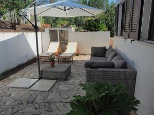 a patio with a couch and an umbrella and chairs at Paraíso das Flores in Pataias