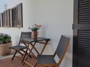 a table with two chairs and a vase with flowers at Paraíso das Flores in Pataias