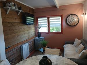 a living room with a couch and a clock on the wall at Le Chalet de Gonnehem in Gonnehem