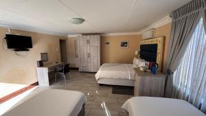 a hotel room with two beds and a television at Guesthouse 116 on McLean in Welkom