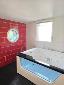 a bathroom with a tub with a window and red tiles at Gîte de la Daudière La Grange in Le Boupère
