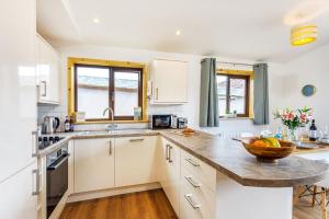 a kitchen with white cabinets and a bowl of fruit on the counter at L54 - Sunny Corner in Truro