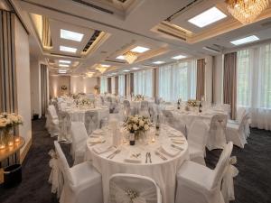 a banquet hall with white tables and white chairs at guestified GRAND AIRPORT Hotel Düsseldorf Ratingen in Ratingen