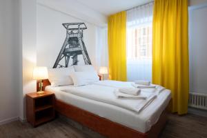 a bedroom with a large bed with yellow curtains at Hotel zur Post in Herne +6 photos