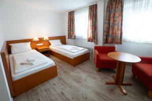 a hotel room with two beds and a red chair at Hotel zur Post in Herne
