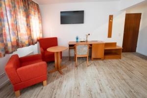a living room with a table and a chair and a desk at Hotel zur Post in Herne