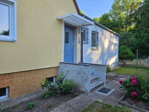 a yellow house with a blue door and some flowers at Haus am Kuhsee in Augsburg