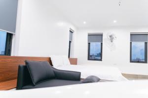 a white bedroom with a bed and windows at R Hotell in Sầm Sơn