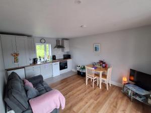 a living room with a couch and a kitchen with a table at Swan Studio Haven in Lisdoonvarna