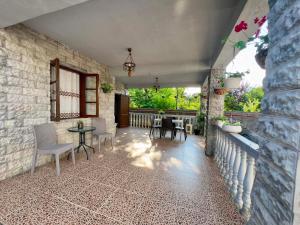 a patio with a table and chairs and a stone wall at Hotel Kobuleti Garden in Kobuleti