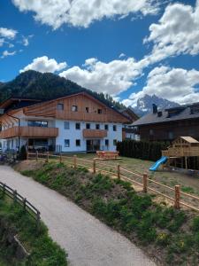 a building with a fence next to a dirt road at Kuenzerhof Apartments in Braies