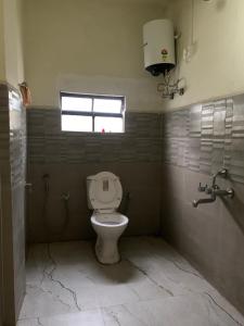 a bathroom with a toilet and a window at The 1802 travellers inn in Shillong