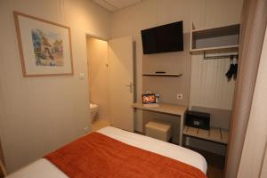 a small room with a bed and a desk with a television at Hôtel Des Trois Gares in Paris +43 photos