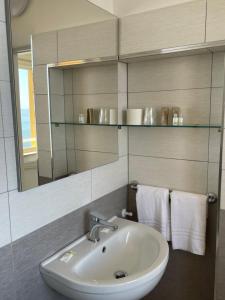 a bathroom with a sink and a mirror and towels at Hotel Le Najadi in Santa Marinella