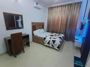 a bedroom with a bed and a desk and a television at Hillmabliz Apartment in Abuja