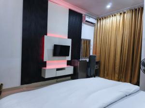 a bedroom with a bed and a tv on a wall at Hillmabliz Apartment in Abuja