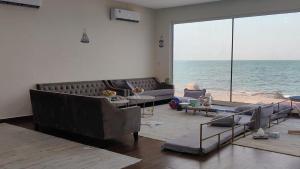 a living room with a couch and a view of the ocean at Alwahyada chalet in Majrá al Ghāf