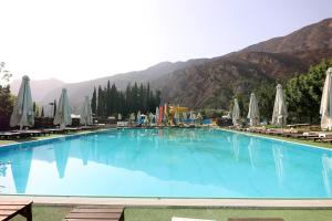 a large blue swimming pool with chairs and umbrellas at Semantron Traditional Village in Diakopto