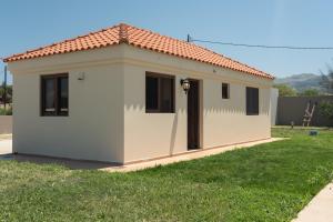a small white building with a red roof at Agios Ioannis Cozy Houses With Private Pool in Tigaki