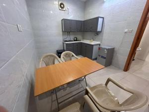 a small kitchen with a wooden table and chairs at سرور للشقق المخدومة in Al Baha