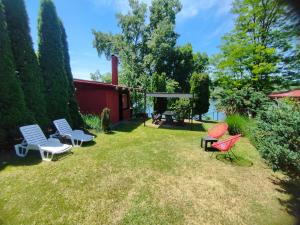 a yard with chairs and tables and a house at Vikendica DRINSKI DAR in Mali Zvornik
