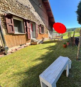 a red umbrella and a bench in front of a house at Joz Une Halte in Saint-Antoine