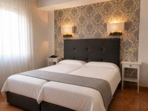 a bedroom with a large bed with two lamps on the wall at Hospedium Hotel Juan II in Toro