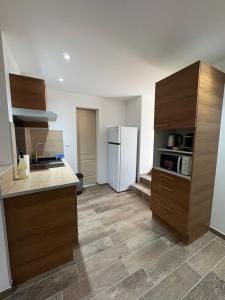 eine Küche mit Holzschränken und einem weißen Kühlschrank in der Unterkunft Suite Maison Roche in Carpentras