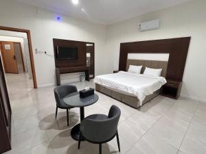 a bedroom with a bed and a table and chairs at سرور للشقق المخدومة in Al Baha