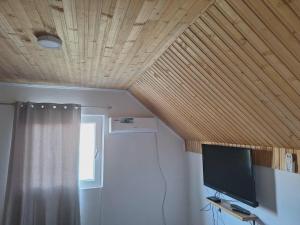 a room with a tv and a wooden ceiling at Horizont Cemerno in Podborina +40 photos