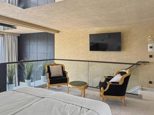 a bedroom with a bed and two chairs and a tv at Eurovea Apartments in Bratislava