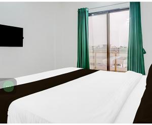 a bedroom with a white bed and a large window at Hotel sai laxmi residency in Lonavala