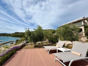 a patio with two chairs and a table next to the water at Robinson house Vitane in Tkon