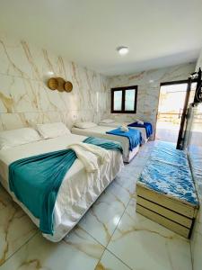 two beds in a room with marble walls at Pousada Sereias de Maragogi in Ponta do Mangue