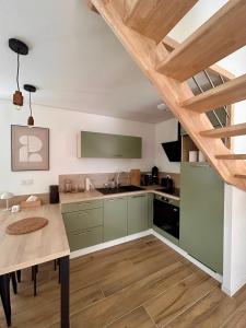 a kitchen with green cabinets and a wooden table at Ker Rev Home Gîte indépendant de charme en longère bretonne in Quimper