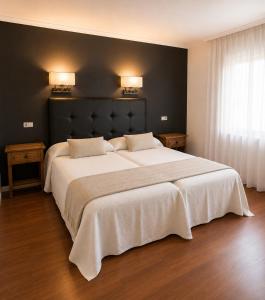 a bedroom with a large white bed with two pillows at Hospedium Hotel Juan II in Toro