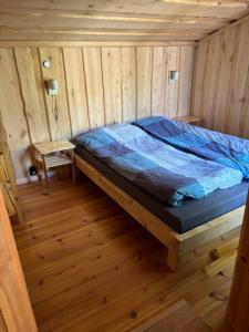 ein Bett in einem Holzzimmer mit Holzboden in der Unterkunft StrandRo 2 in Hirvensalmi