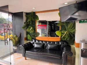 a black leather couch in a room with plants at Hotel Portal Central in Medellín