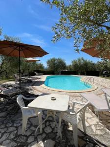 a pool with a table and chairs and an umbrella at Eclissi casa vacanza SOLE in Casalini