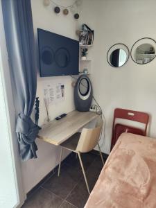 a desk with a television on a wall at Studio cosy sans vis-à-vis in Vernon