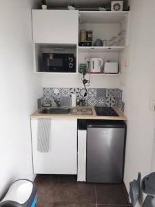 a small kitchen with white cabinets and a sink at Studio cosy sans vis-à-vis in Vernon