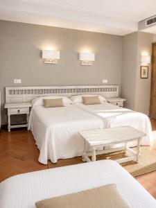 a bedroom with two beds with white sheets and tables at Hospedium Hotel Juan II in Toro