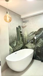 a bathroom with a white tub and plants on the wall at Kvariati House in Kvariati