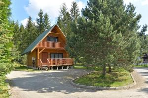 a large wooden cabin with a porch and a tree at Leśna Polana in Baligród