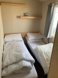 two beds in a small room with white sheets at Julie's in Ingoldmells