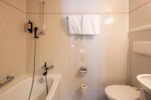 a bathroom with a tub and a toilet and a sink at Hotel Alpina in Zernez +42 photos