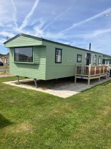 a green tiny house with a porch and a yard at Julie's in Ingoldmells