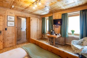 a room with a bed and a desk at Hotel Alpina in Zernez