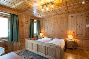 a bedroom with a large bed in a room with wooden walls at Hotel Alpina in Zernez