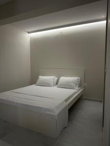 a white bed with white sheets and pillows on it at Kostas apartaments in Korinthos